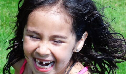 Young girl laughing, with two front teeth missing