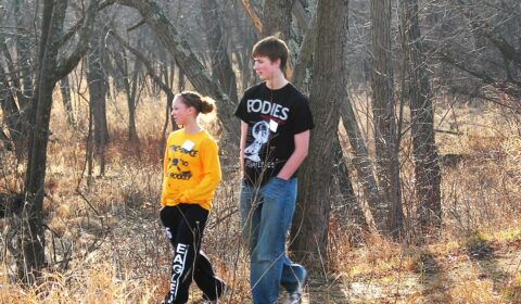 Two high school students, a girl and a guy, walking outside in the late autumn