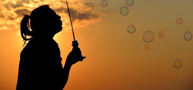 Woman blowing bubbles with a sunset in the background